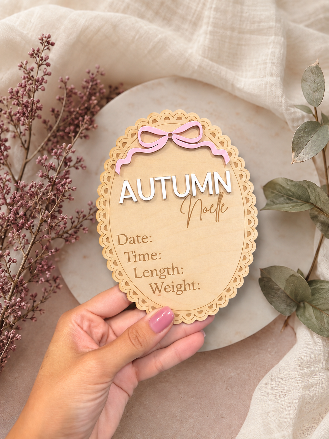 Personalized scalloped wooden birth announcement with a pink bow, Autumn Noelle name lettering, and spaces for birth details