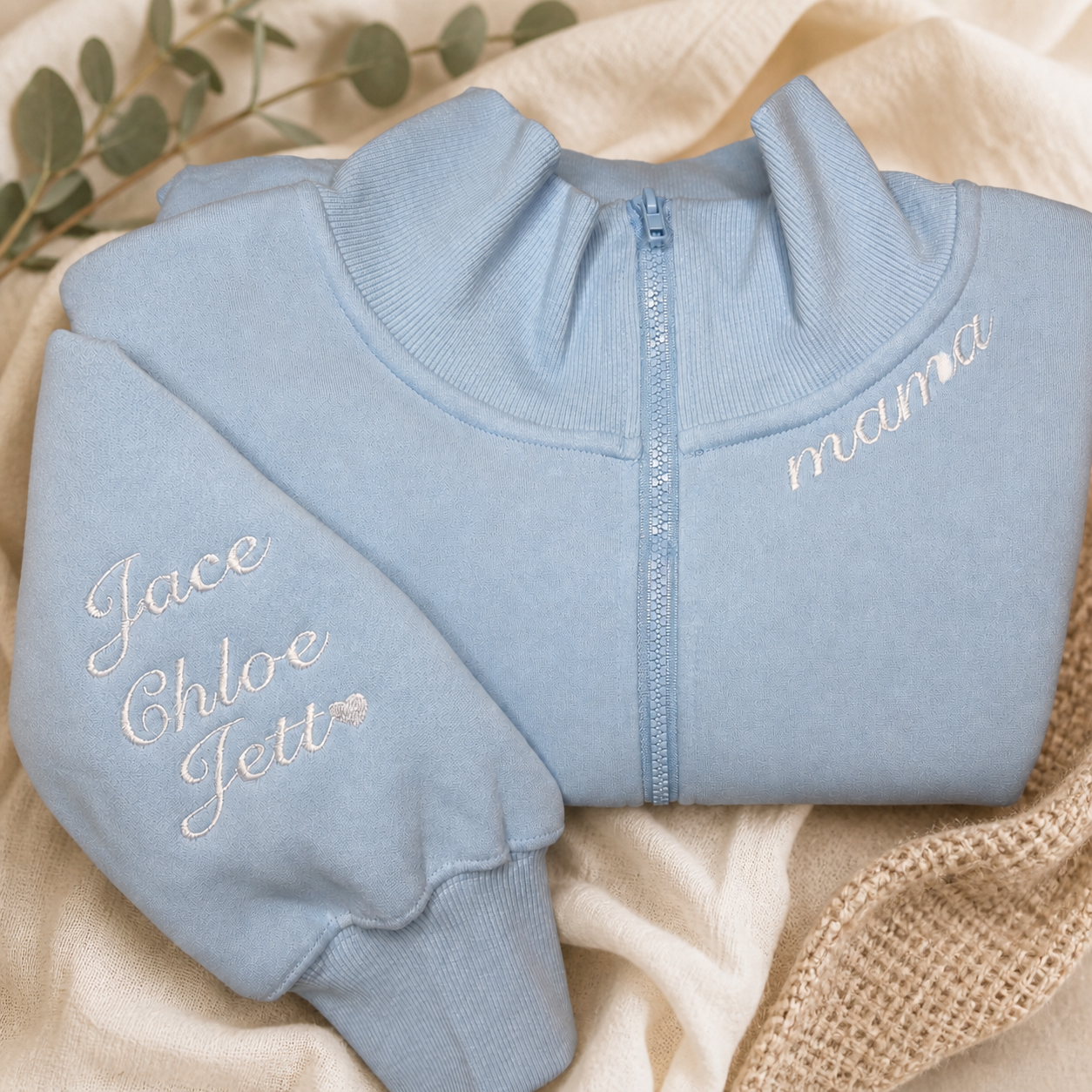 Pale blue custom embroidered sweatshirt styled on soft ivory linen with natural woven accents