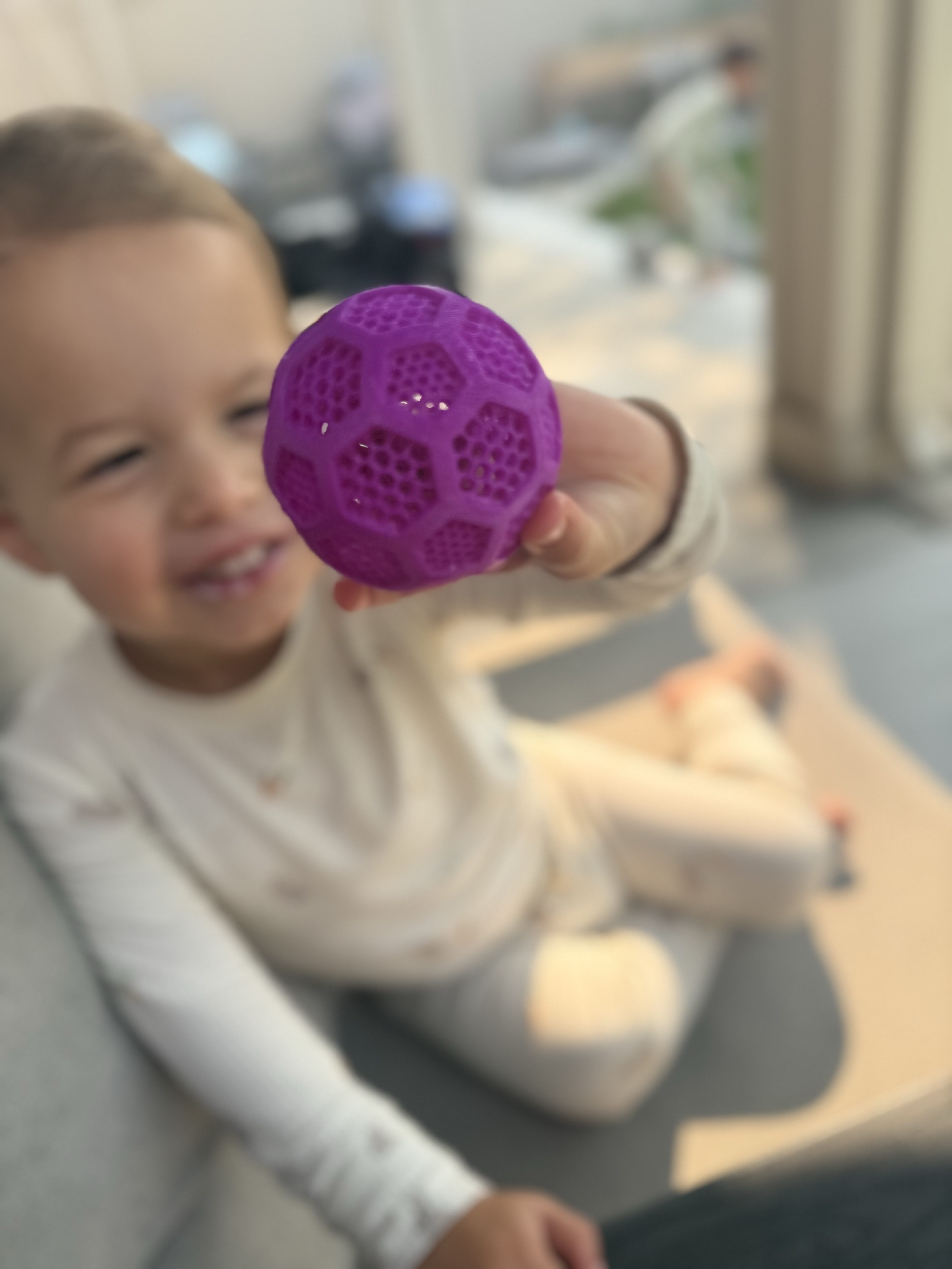 Child holding a bright purple 3D-printed lattice ball